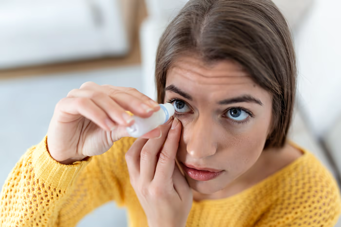 Paciente aplicando colírio lubrificante — olho seco crônico em usuárias de lentes de contato é uma queixa frequente e uma das principais motivações para considerar cirurgia refrativa. Ilustração de banco de imagens.