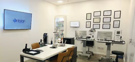 Sala de consulta da Ortolan Oftalmologia com equipamentos oftalmológicos e diplomas na parede